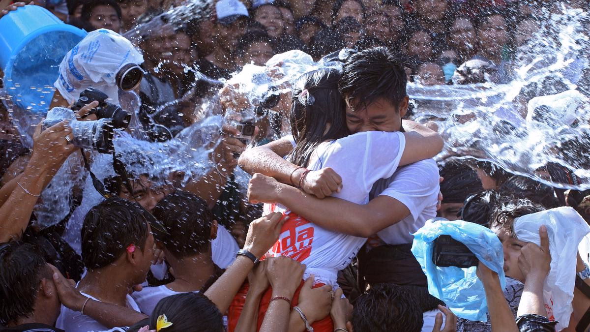 Ribuan pemuda dan pemudi Banjar Kaja Sesetan saling tarik-menarik di jalanan desa yang basah, disiram air dari bambu oleh para tetua, dalam cahaya sore Ngembak Geni yang penuh tawa dan kegembiraan